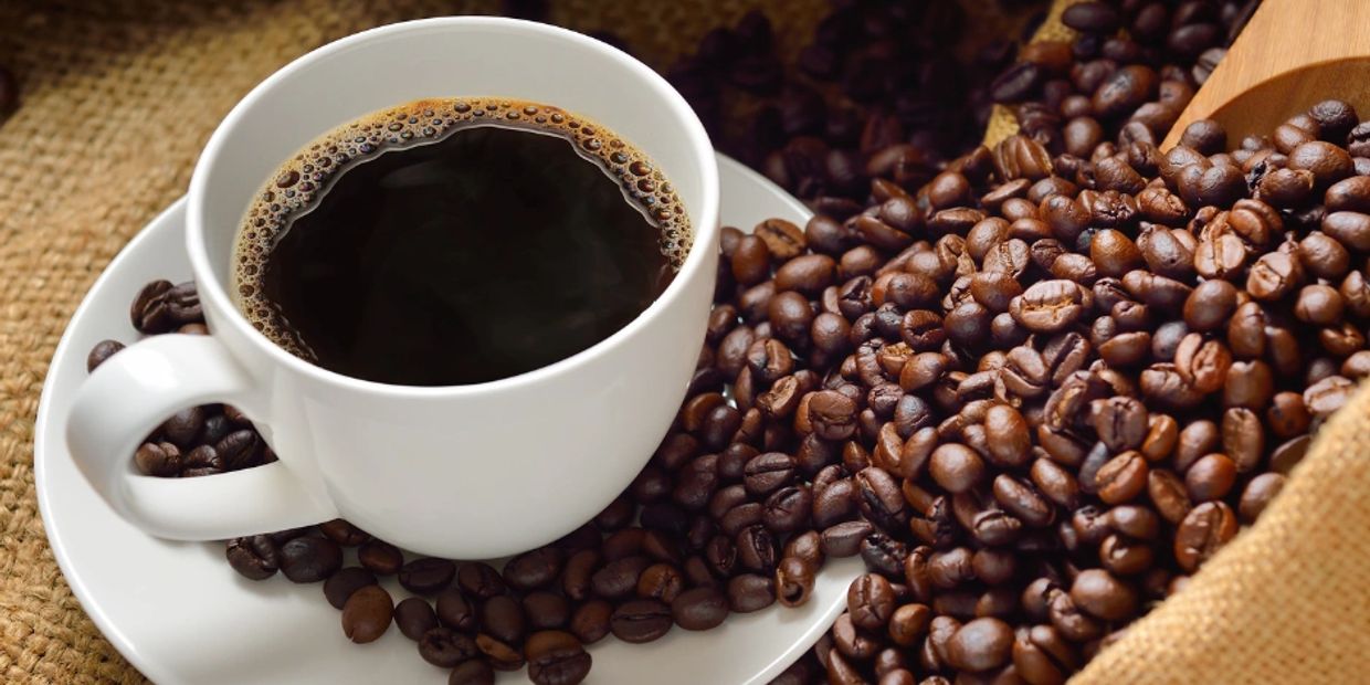 Cup of coffee with coffee beans spilling from a sack.