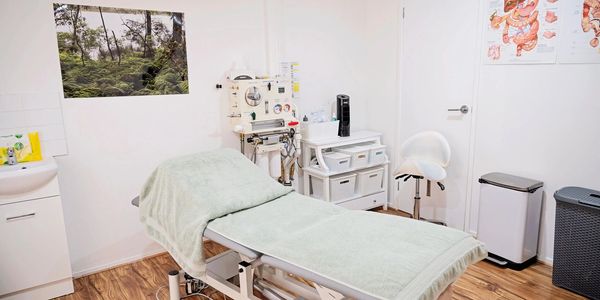 Clean and tidy medical treatment room with bed and equipment.