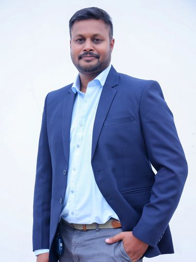 Man in a blue blazer and light blue shirt posing confidently.