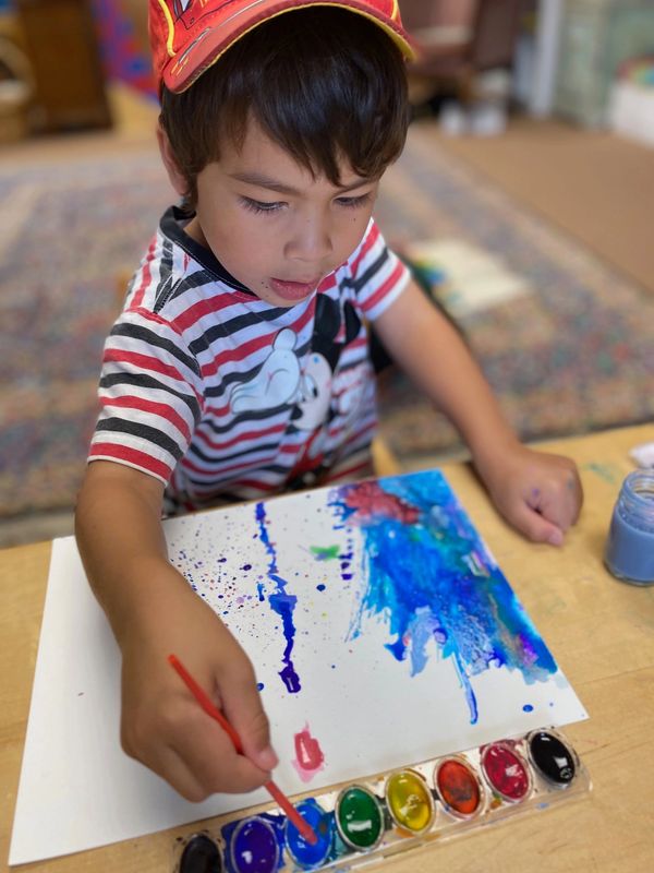 A picture of the boy painting on the paper