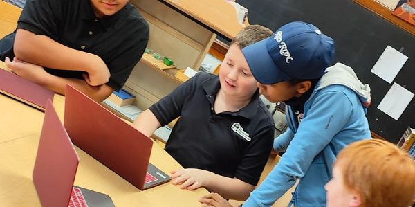 A picture of the kids looking at the laptop