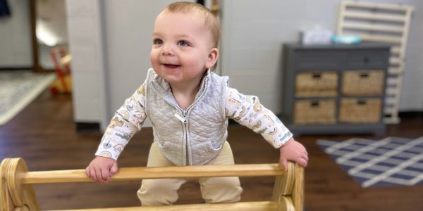 A picture of a cute baby climbing on a wooden furniture 