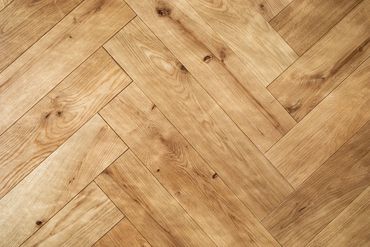 Close-up of a wooden parquet floor with a herringbone pattern.