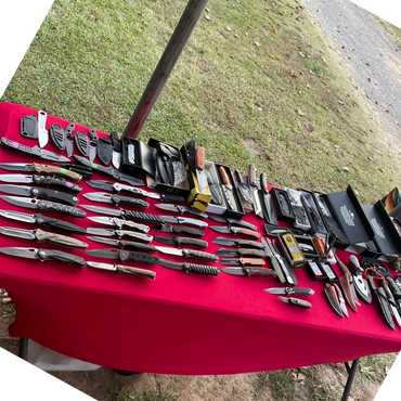 A table covered with various knives and knife accessories on a red cloth.