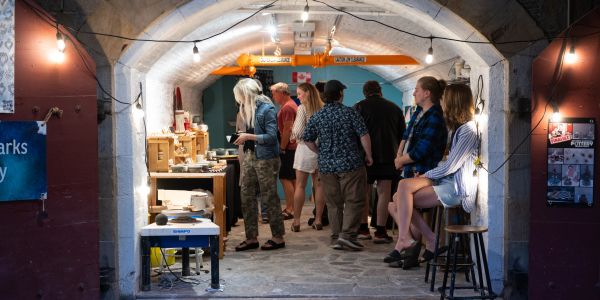 People view art in a stone-arched gallery.