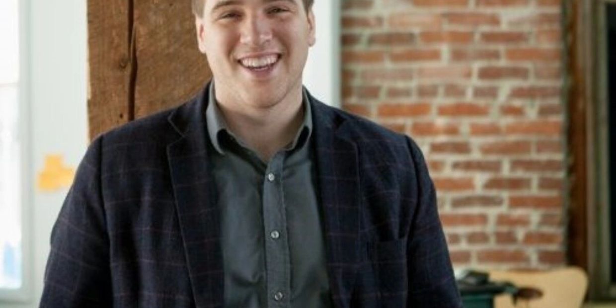 Young man smiling in a casual office setting.