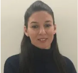 Portrait of a woman with dark hair and a black turtleneck against a plain background.