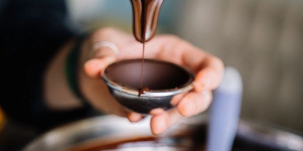 Pouring melted chocolate into a small bowl.