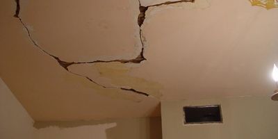 Ceiling with large cracks and damage.