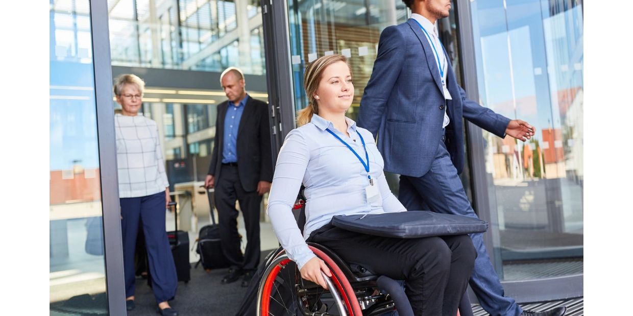 Businesswoman in wheelchair leaving office with colleagues.