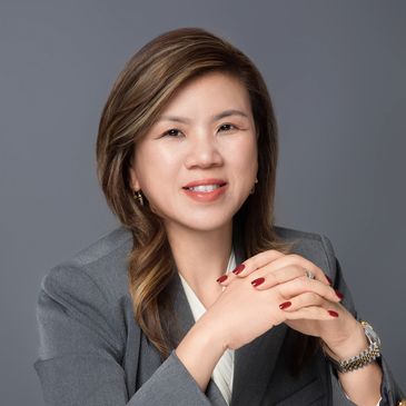 Professional woman in a gray blazer smiling confidently.