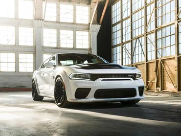 White Dodge Charger SRT parked in a sunlit industrial garage.