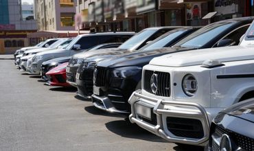 A line of luxury cars parked along a street in an urban area.