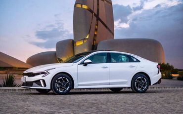 White sedan parked in front of a modern architectural structure at dusk.