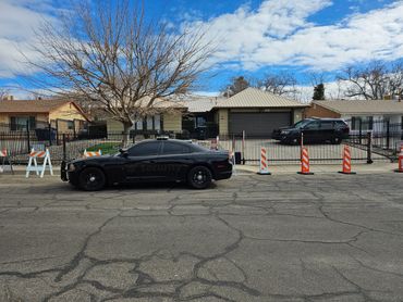 Security vehicles parked outside a fenced residential property on a clear day.