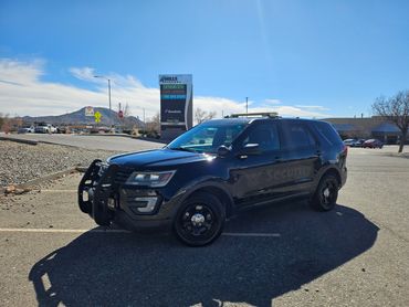Black security SUV parked in a shopping center parking lot on a sunny day.