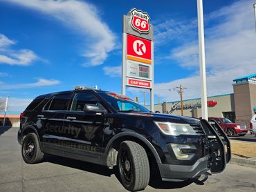 Black security SUV parked near a Phillips 66 gas station under a blue sky.