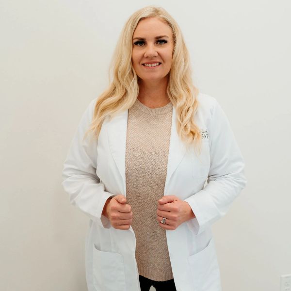 Woman in a white lab coat smiling at the camera.