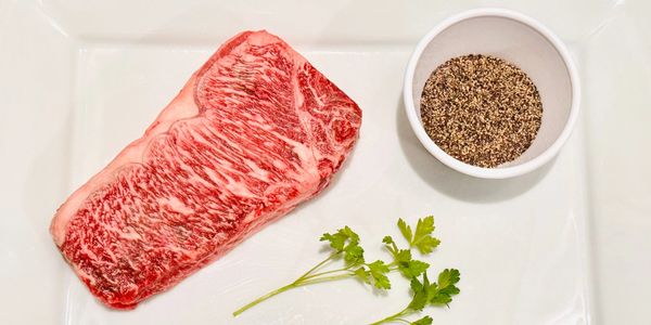 Raw marbled steak with seasoning and parsley.