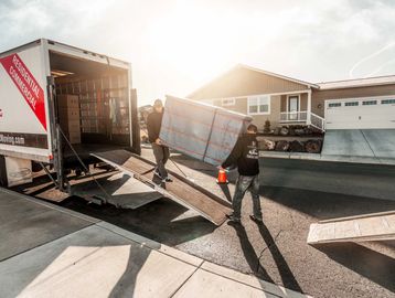 Bend Brothers Moving truck with employees carefully loading furniture wrapped in protective pads
