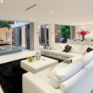 All white living room with white furniture, big windows, and recessed lighting.