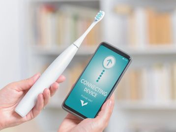 Electric toothbrush held up against smart phone to which it is connected by bluetooth 