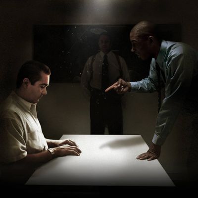 A man sitting in a dimly lit room being interrogated by the police.