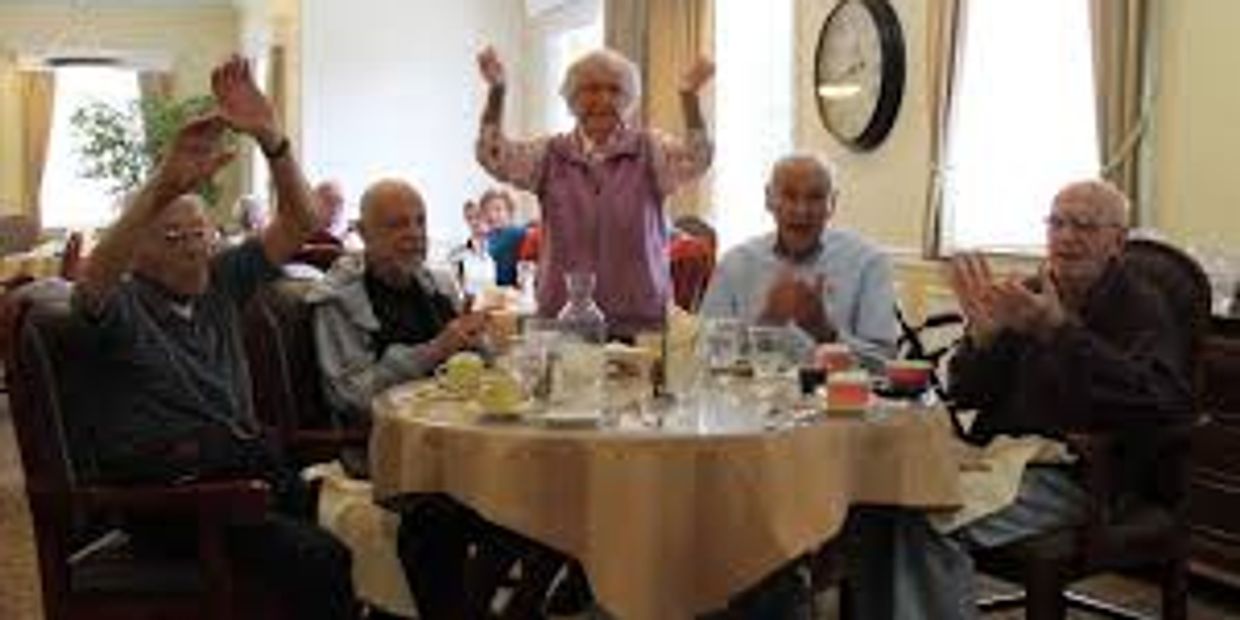 Group of elderly people sitting at a table smiling and happy.