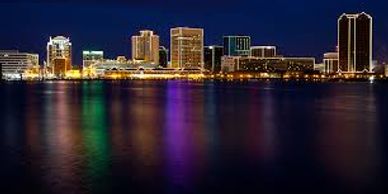 Norfolk skyline at night with buildings illuminated. Your Hampton Movers will travel to Norfolk.