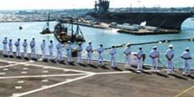 Sailors formation on carrier with aircraft carrier in background. Hampton movers support military. 