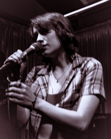 A singer passionately performing with a microphone in a dimly lit venue.