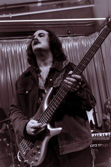 Musician passionately playing bass guitar on stage.