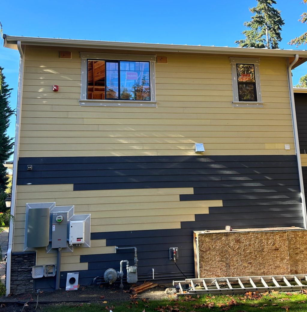 House side with partially painted siding in dark and beige colors.