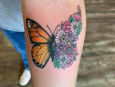 Monarch Butterfly and flowers on a lady’s forearm by Wojo.