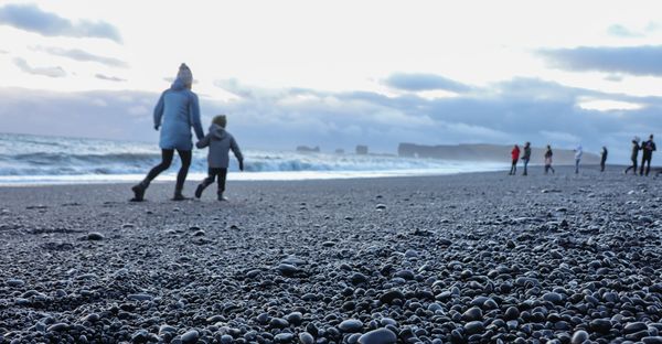 A woman and her son holding hands on family holiday at Reynisfjara Beach in Iceland