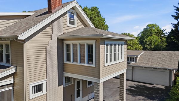 View of a beige house with a brick chimney and a garage.