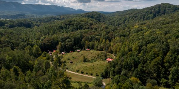 Aerial view of green forested hills and scattered red-roofed houses.