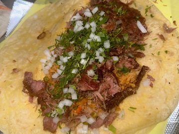 A taco filled with grilled meat, chopped onions, and fresh cilantro.