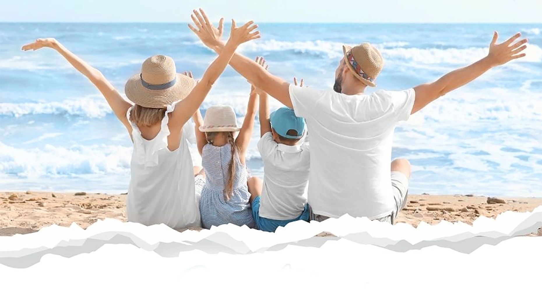 Family enjoying a sunny day at the beach with arms raised joyfully.