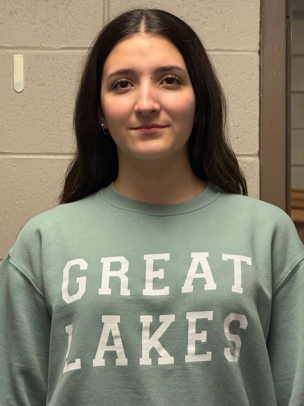 Young woman wearing a green sweatshirt with "GREAT LAKES" text.