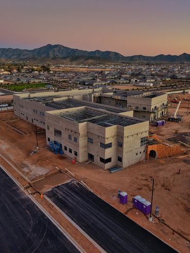 A large building under construction at dusk with mountains in the background.