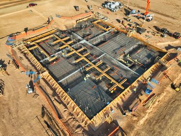 Aerial view of a construction site with workers and concrete foundation work.