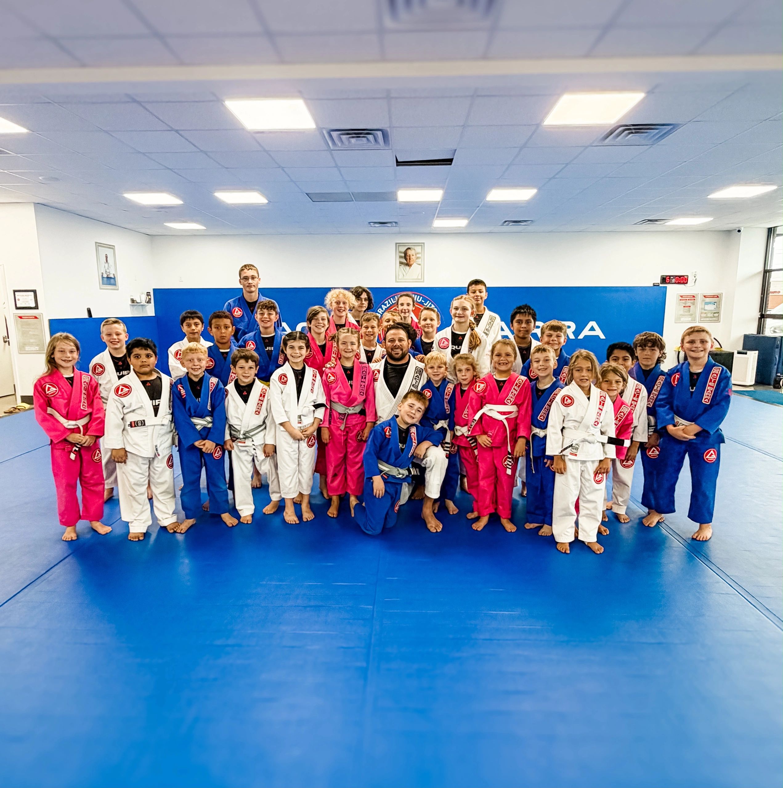 Group of kids and instructors in martial arts gis posing for a photo.