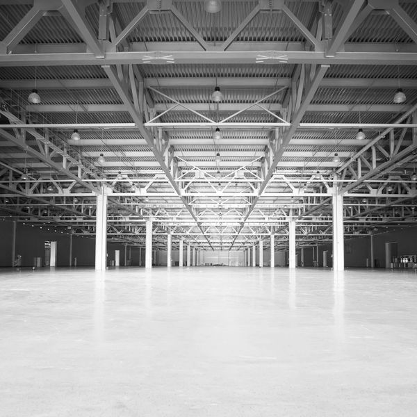 Empty industrial warehouse with metal beams and high ceiling lights.