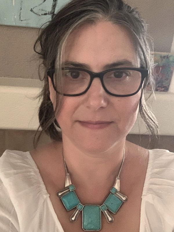 Woman with glasses wearing a turquoise statement necklace.