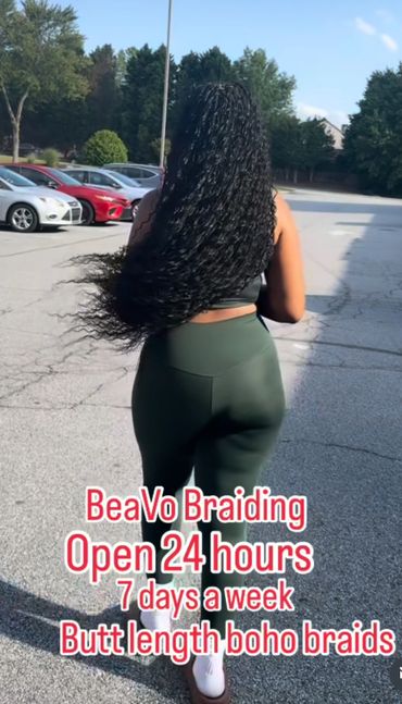 Woman with long boho braids walking in a parking lot.