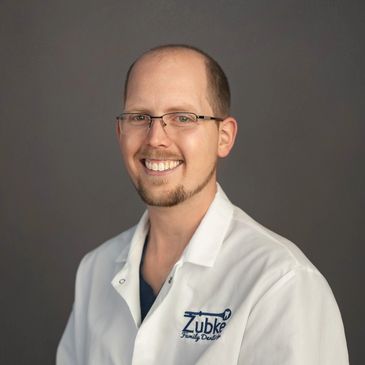 Smiling male dentist in a white coat.