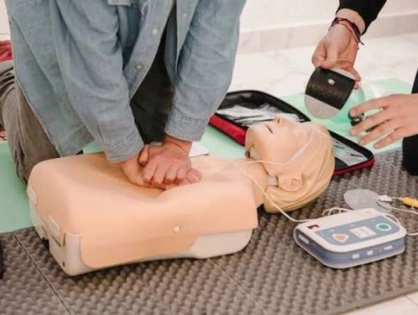 Person performing CPR on a training dummy with AED.