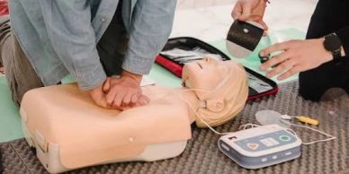 Person performing CPR on a training dummy with AED.