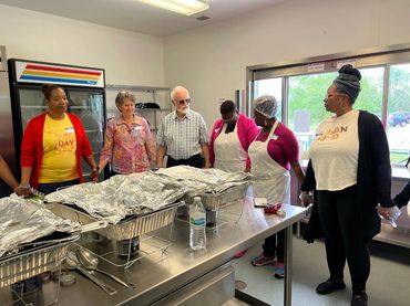 Group gathered together in kitchen praying before serving.